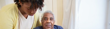 woman helping older man into chair