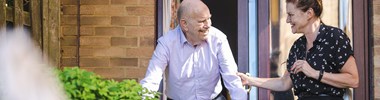 smiling older man with woman supporting him walking in garden